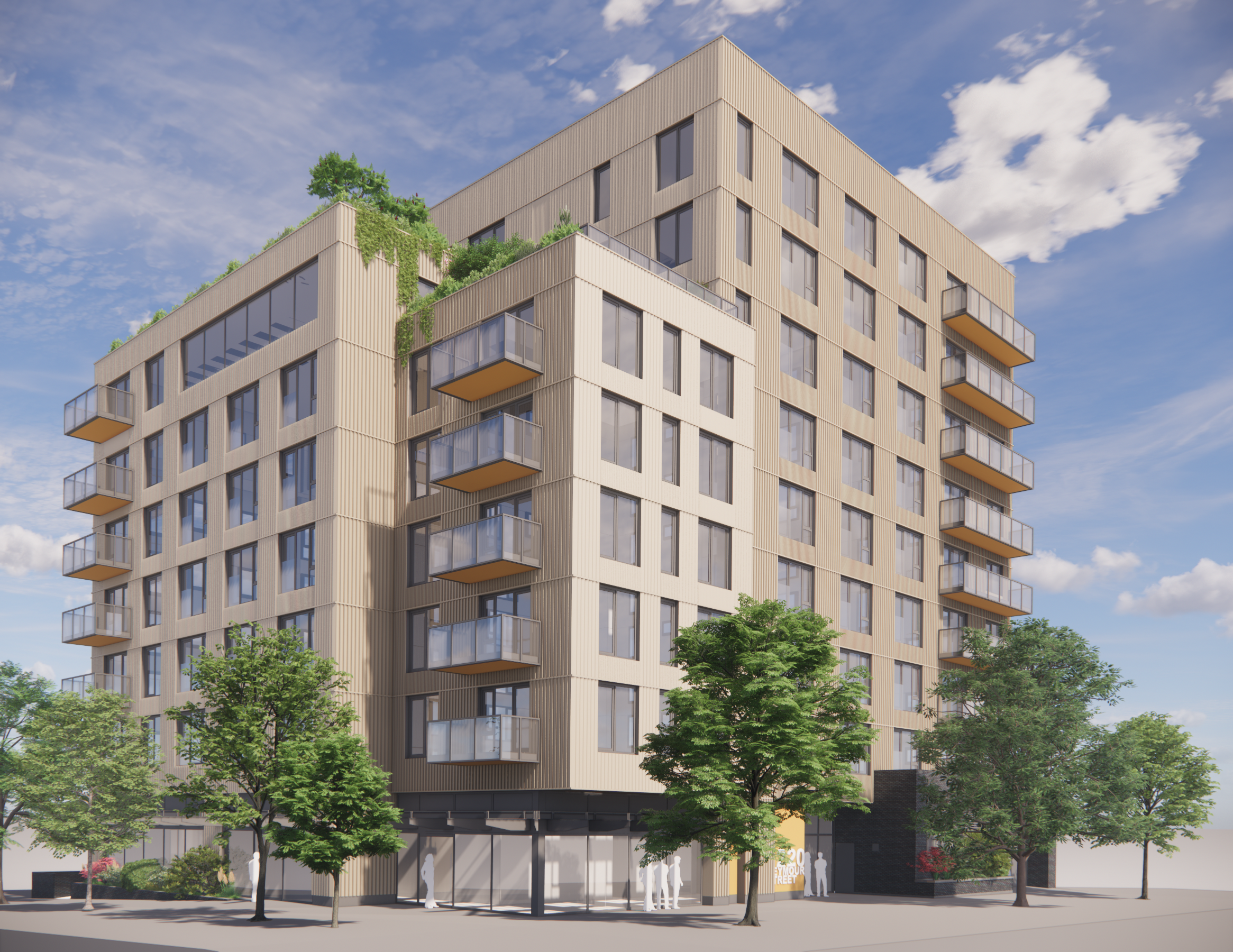 A modern mid-rise apartment building with beige exterior cladding, glass balconies, and rooftop greenery, viewed from the street corner with trees along the sidewalk.