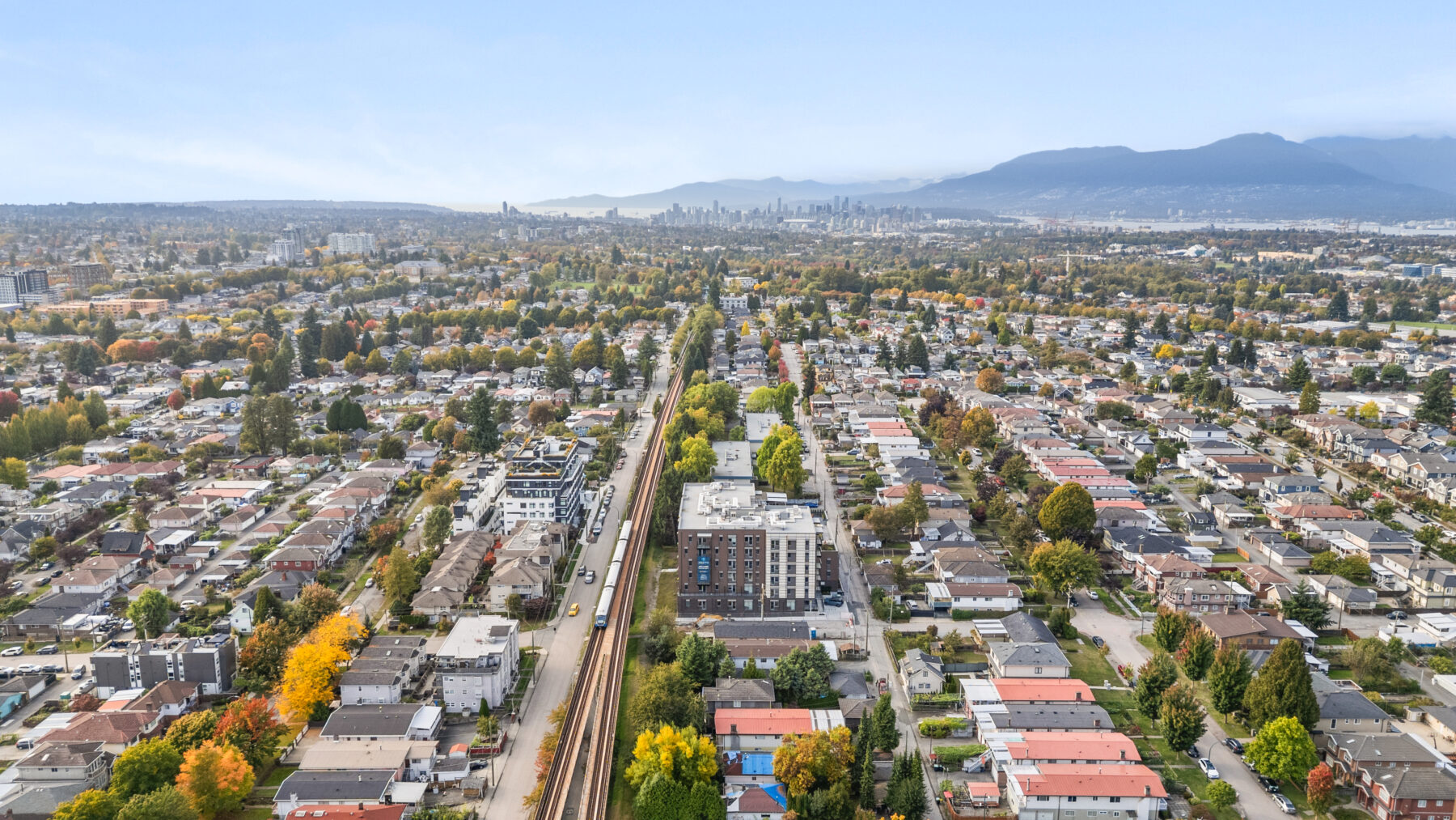Aerial view of McHardy affordable housing building in Vancouver, surrounded by residential homes and mountains in the distance.