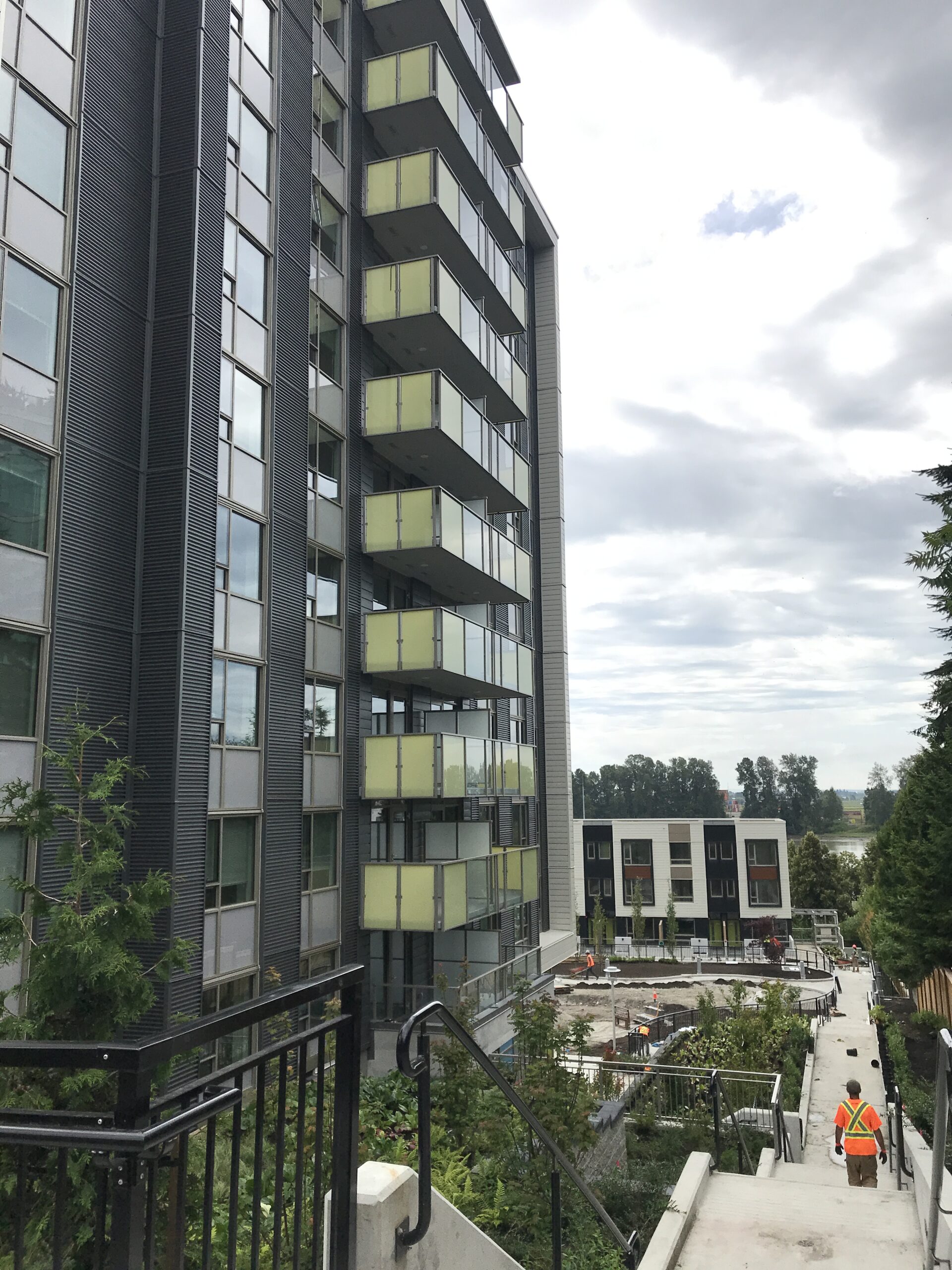 Side view of a high-rise residential building with balconies overlooking a stepped walkway.