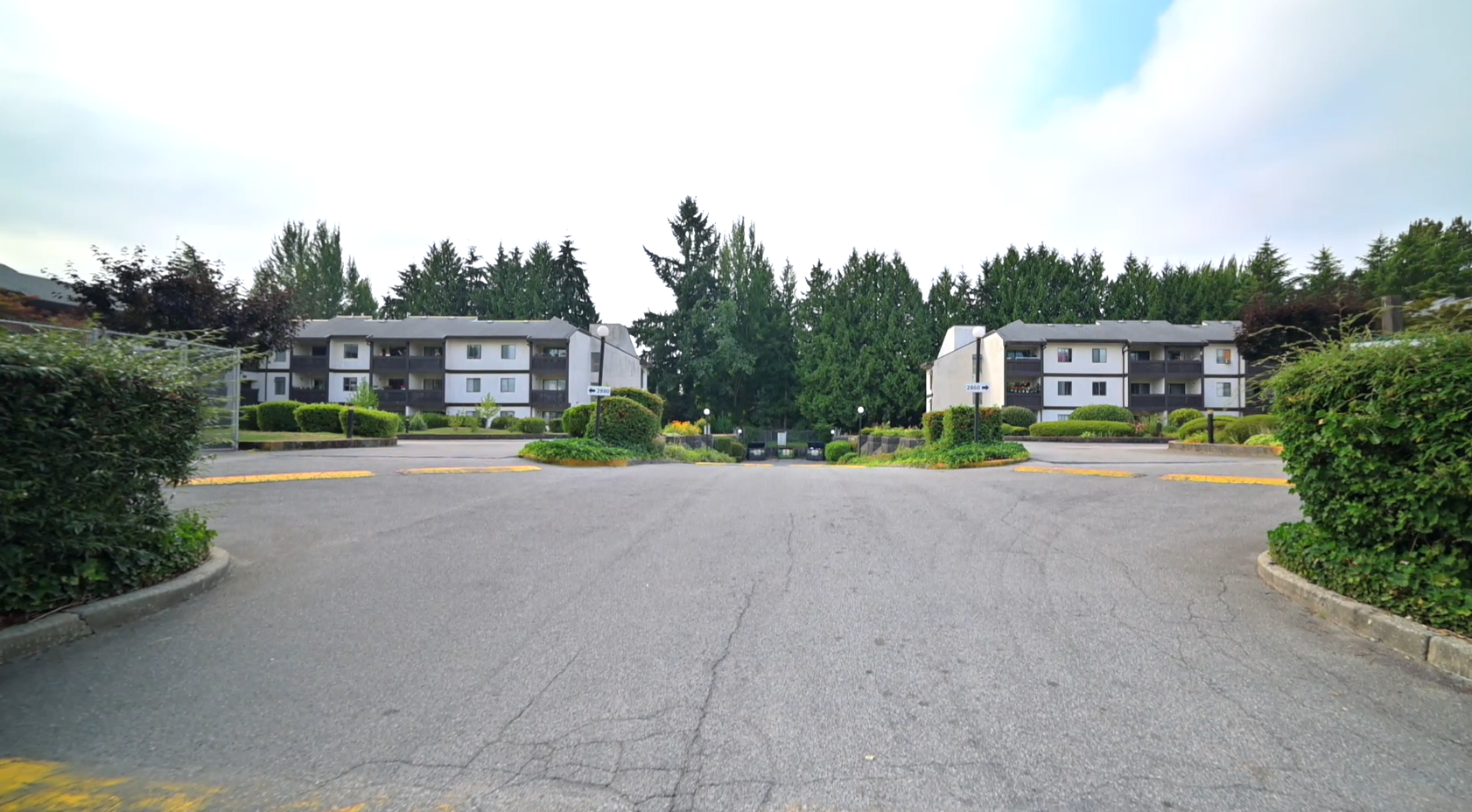 Front view of Packard Housing Co-op in Coquitlam, showing two low-rise buildings with landscaped greenery and wide driveway.