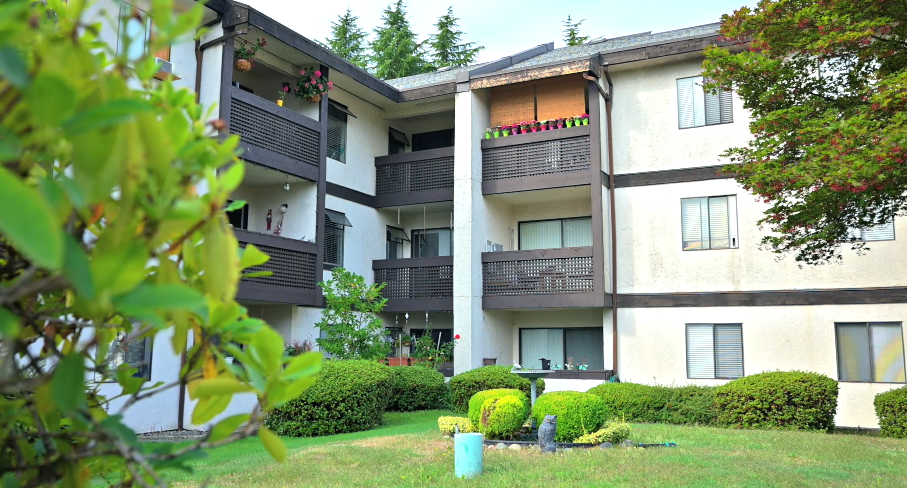 Front view of Packard Housing Co-op in Coquitlam with three stories, balconies, and landscaped greenery.