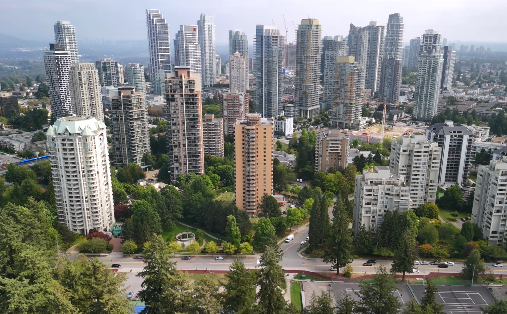 Aerial view of Burnaby city skyline with high-rise buildings, green spaces, and tree-lined streets.