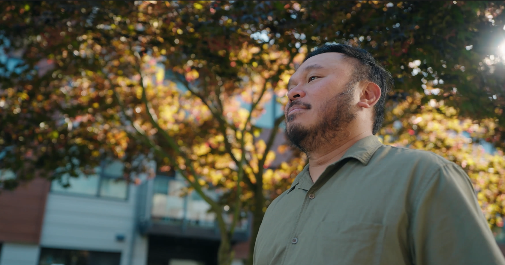 A co-op housing member standing outdoors near his home, reflecting on safety and stability in a long-term community.