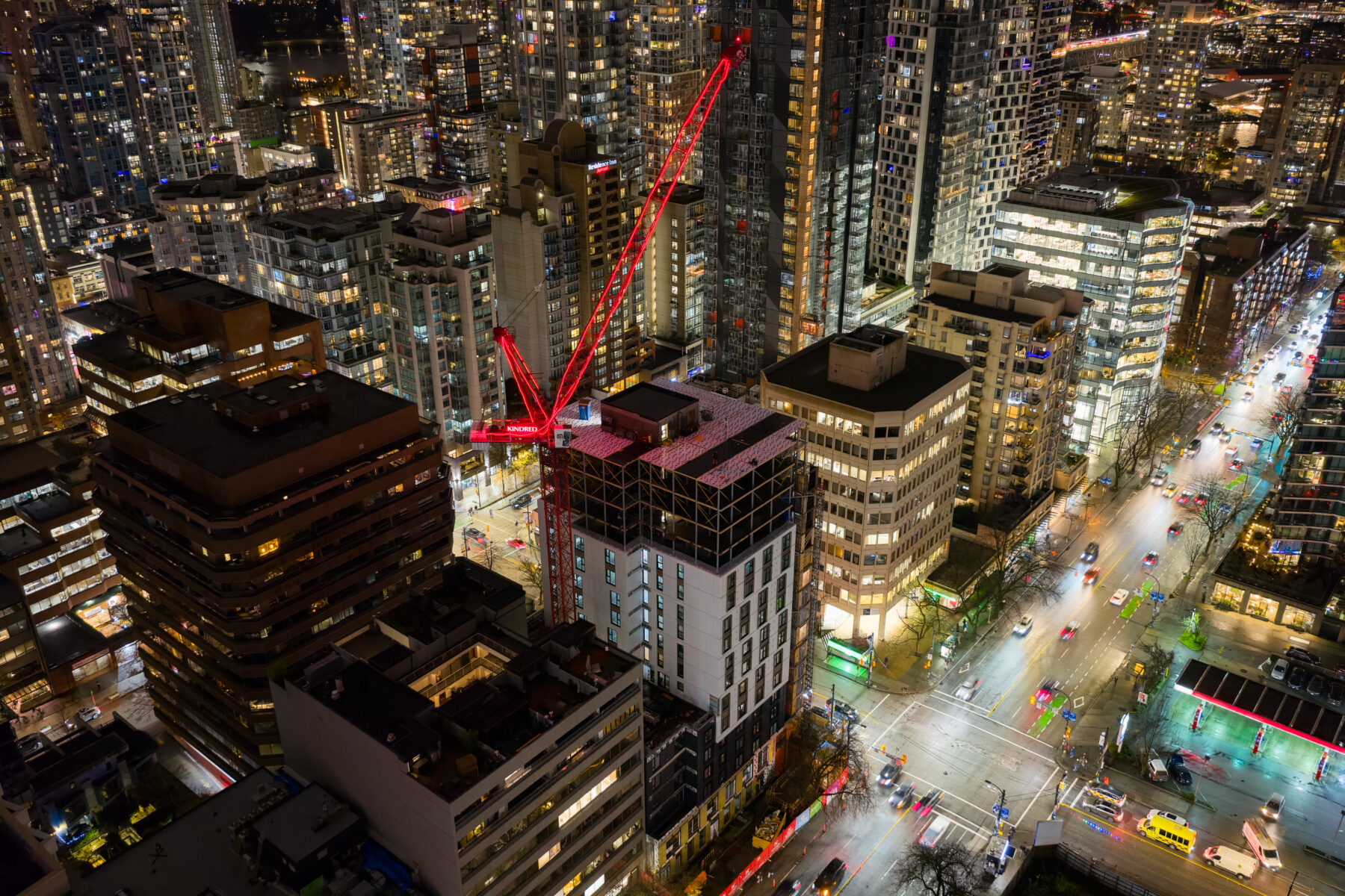 Aerial nighttime view of downtown Vancouver showing high-rise residential buildings and an active housing development within the city’s urban core.